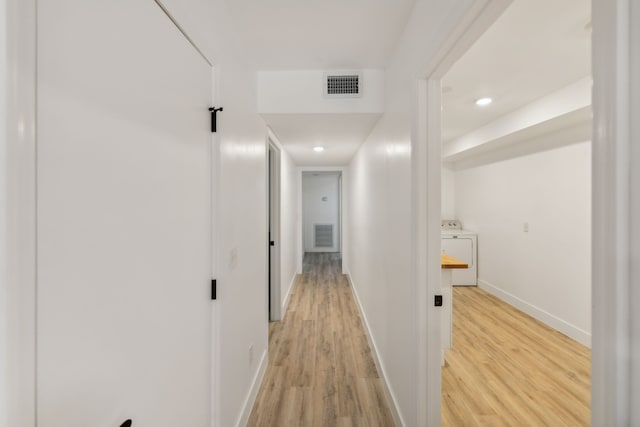 hall with light hardwood / wood-style flooring and washer / dryer