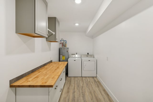 washroom featuring washer and clothes dryer, cabinets, electric water heater, water heater, and light hardwood / wood-style floors