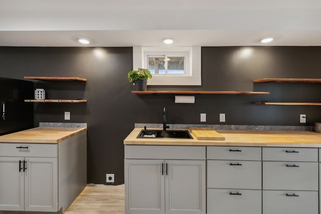 bar featuring butcher block countertops, gray cabinetry, and sink