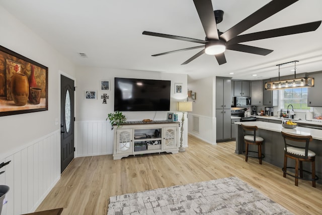 living room with ceiling fan, light wood-type flooring, and sink