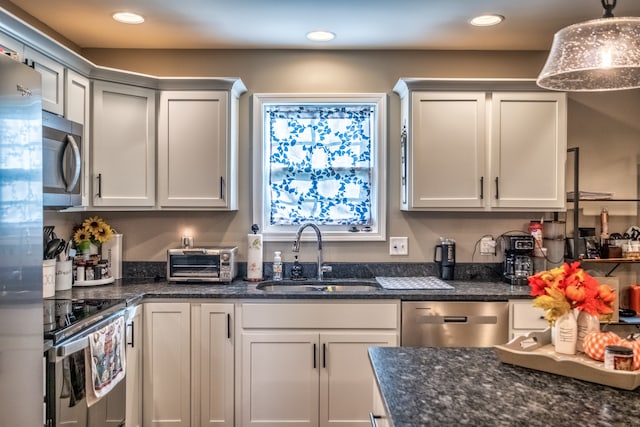 kitchen with white cabinetry, sink, dark stone counters, pendant lighting, and appliances with stainless steel finishes