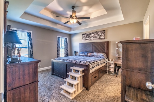 carpeted bedroom with a tray ceiling and ceiling fan