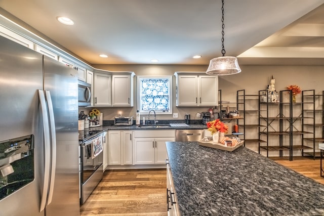 kitchen featuring white cabinets, pendant lighting, light hardwood / wood-style floors, and stainless steel appliances