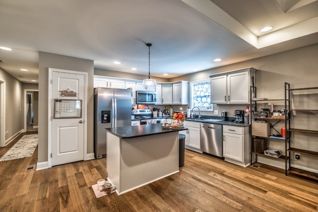 kitchen featuring hardwood / wood-style flooring, a center island, hanging light fixtures, and appliances with stainless steel finishes