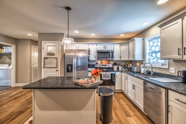 kitchen featuring light wood-type flooring, stainless steel appliances, sink, pendant lighting, and a center island