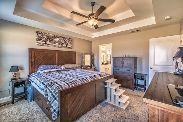 bedroom featuring ceiling fan, light carpet, and a tray ceiling