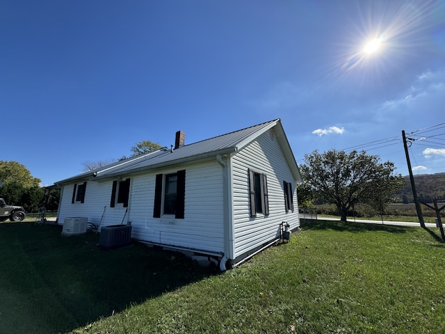 view of side of home with a lawn and cooling unit