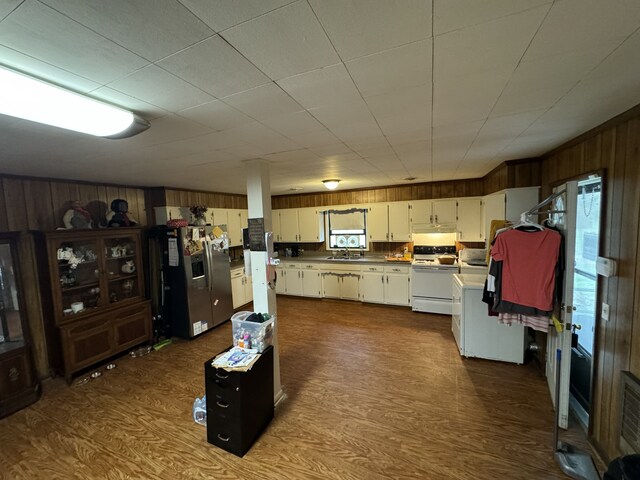 kitchen with dark hardwood / wood-style floors, wood walls, stainless steel fridge with ice dispenser, and white stove