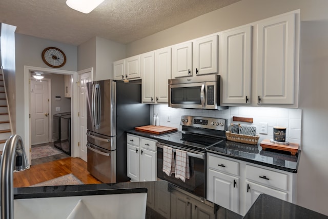 kitchen with backsplash, white cabinetry, dark hardwood / wood-style flooring, and appliances with stainless steel finishes