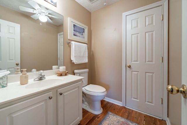 bathroom featuring vanity, ceiling fan, toilet, a textured ceiling, and wood-type flooring