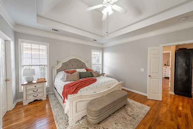 bedroom featuring ceiling fan, dark hardwood / wood-style floors, ornamental molding, and a tray ceiling