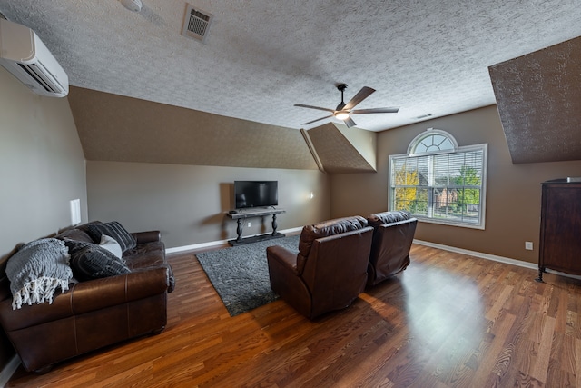 living room with dark wood-type flooring, an AC wall unit, vaulted ceiling, ceiling fan, and a textured ceiling