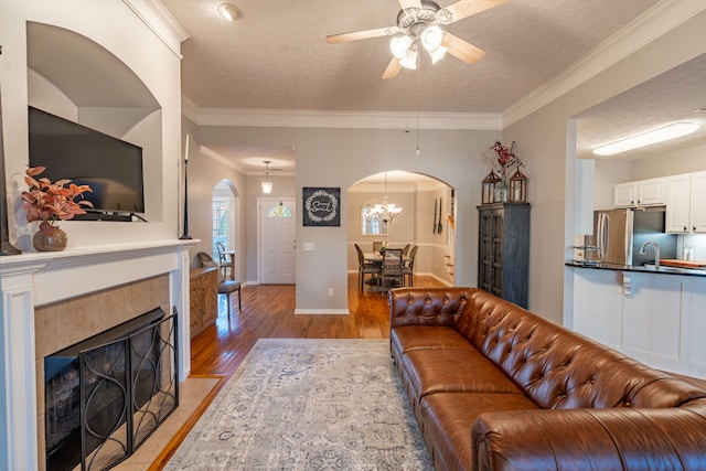 living room with a textured ceiling, ceiling fan, crown molding, and light hardwood / wood-style flooring