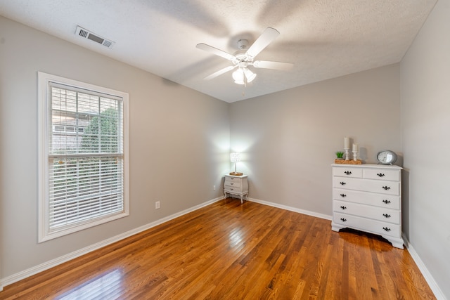 empty room featuring hardwood / wood-style floors, ceiling fan, and a textured ceiling