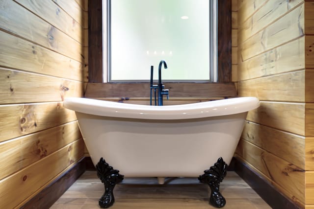 bathroom with a tub to relax in and wooden walls