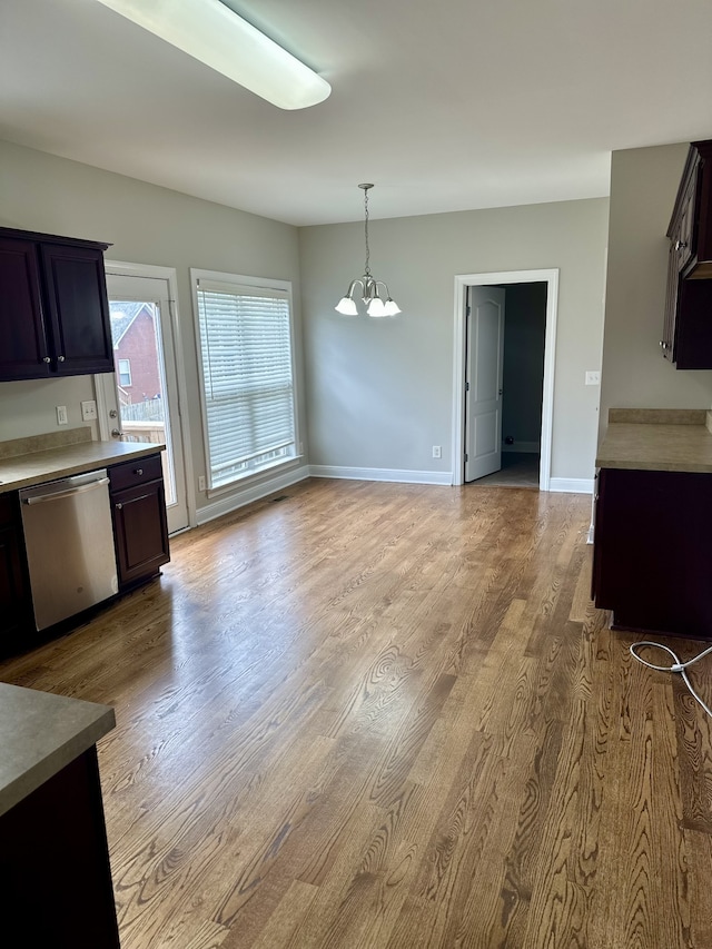 kitchen with light wood-type flooring, stainless steel dishwasher, dark brown cabinetry, pendant lighting, and a chandelier