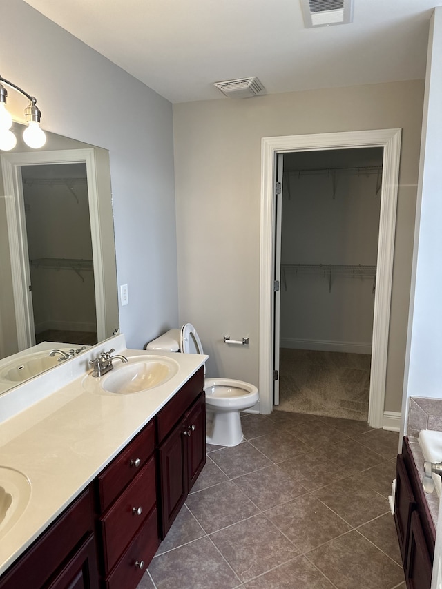 bathroom featuring tile patterned floors, a tub to relax in, vanity, and toilet