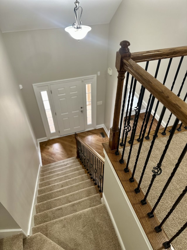 entrance foyer featuring hardwood / wood-style floors, lofted ceiling, and a notable chandelier