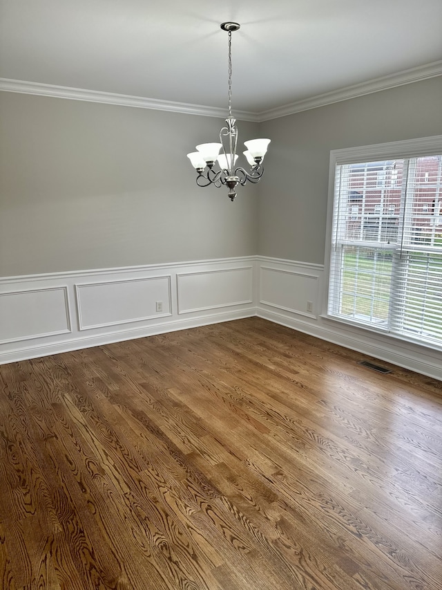 unfurnished dining area with hardwood / wood-style flooring, crown molding, and a chandelier