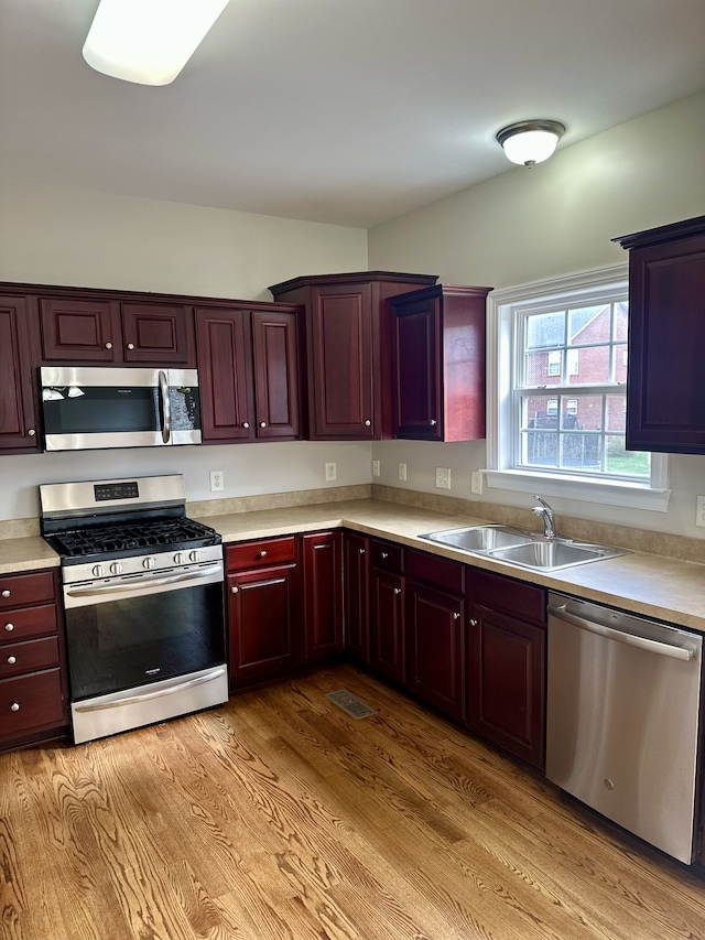 kitchen with appliances with stainless steel finishes, light hardwood / wood-style flooring, and sink