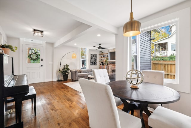 dining area featuring ceiling fan, beamed ceiling, and wood-type flooring