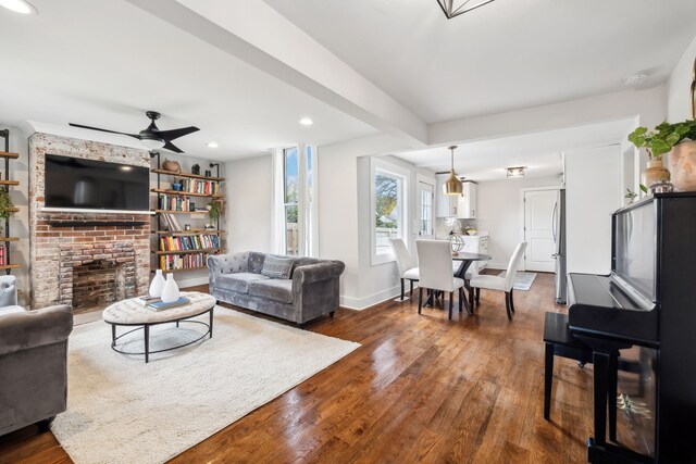 living room with dark hardwood / wood-style floors, ceiling fan, and a brick fireplace