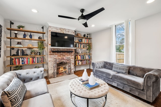 living room featuring ceiling fan, a fireplace, and light hardwood / wood-style flooring