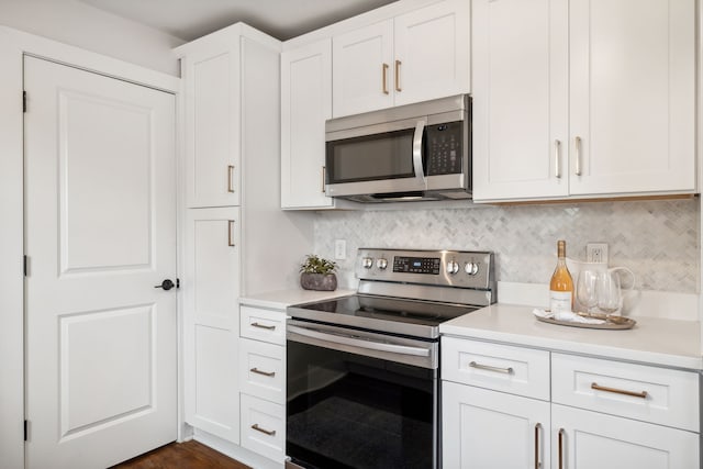 kitchen featuring tasteful backsplash, white cabinetry, dark wood-type flooring, and stainless steel appliances