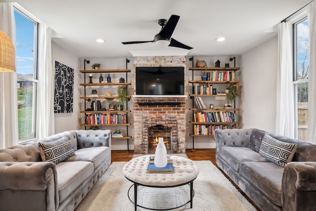 living room featuring hardwood / wood-style flooring, a brick fireplace, a wealth of natural light, and ceiling fan