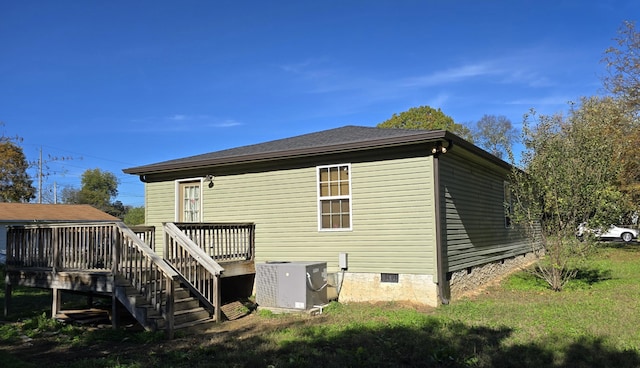 back of house with central AC unit, a deck, and a lawn