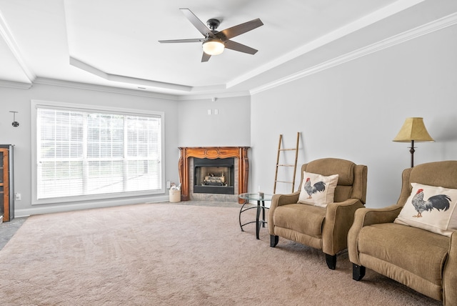 living area with light carpet, a raised ceiling, ceiling fan, and crown molding