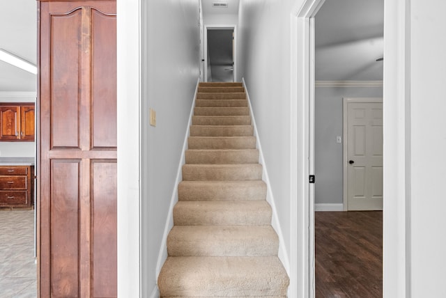 stairs with wood-type flooring and ornamental molding