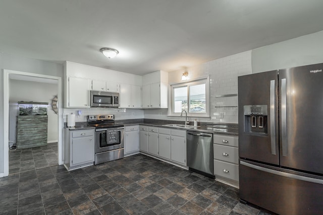 kitchen with backsplash, stainless steel appliances, white cabinetry, and sink