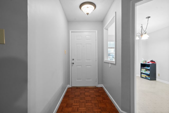 doorway to outside with dark parquet floors and a textured ceiling