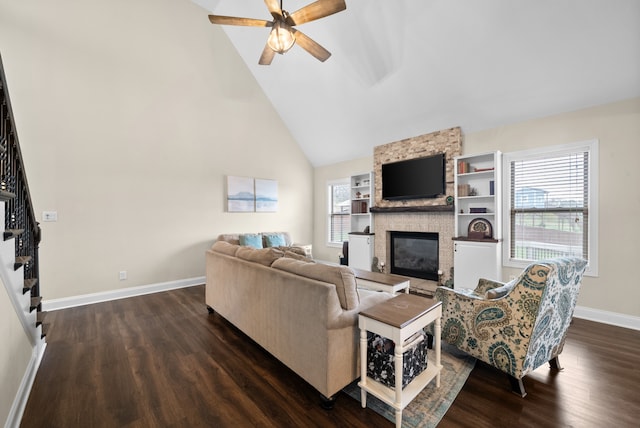 living room featuring a healthy amount of sunlight, a stone fireplace, and dark wood-type flooring