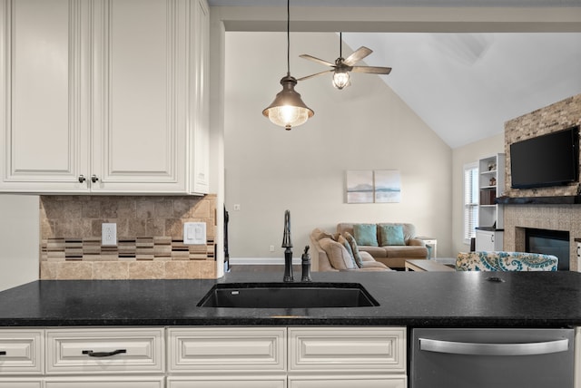 kitchen with white cabinets, a stone fireplace, sink, ceiling fan, and tasteful backsplash