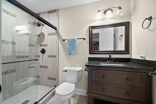 bathroom featuring vanity, a shower with shower door, and toilet