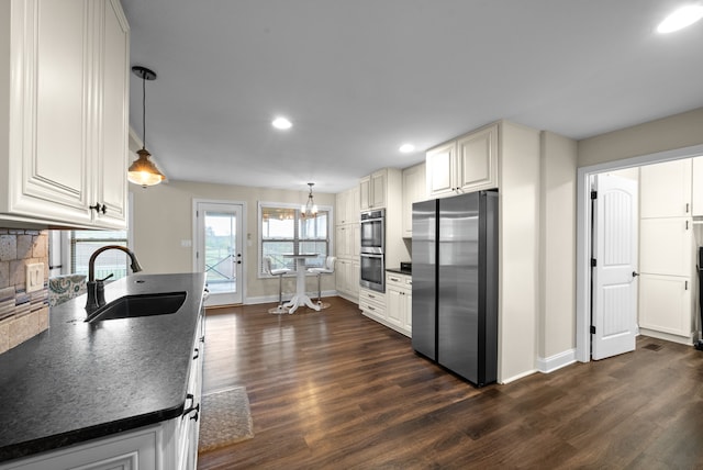 kitchen with pendant lighting, dark hardwood / wood-style flooring, sink, and stainless steel appliances