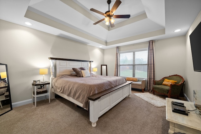 carpeted bedroom with a tray ceiling and ceiling fan