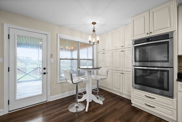 kitchen with hanging light fixtures, double oven, dark hardwood / wood-style flooring, white cabinetry, and a chandelier