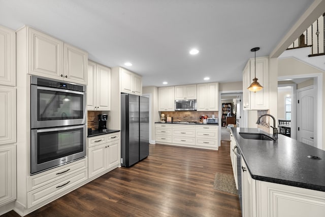 kitchen with dark hardwood / wood-style flooring, backsplash, stainless steel appliances, sink, and decorative light fixtures