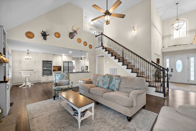 living room with hardwood / wood-style floors, ceiling fan with notable chandelier, and high vaulted ceiling