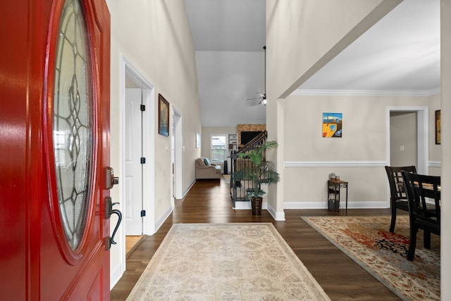 foyer entrance with ceiling fan, high vaulted ceiling, dark wood-type flooring, and ornamental molding