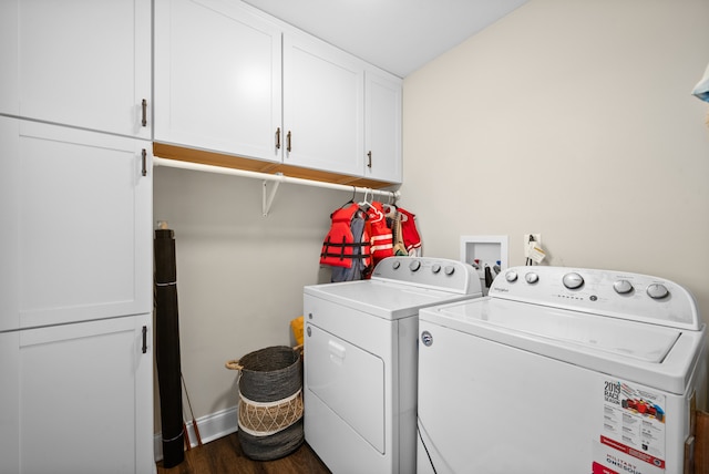 clothes washing area with separate washer and dryer, dark wood-type flooring, and cabinets