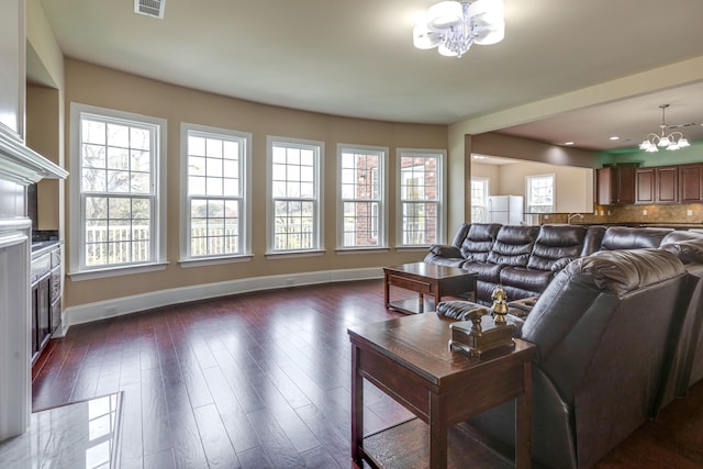 living room with dark wood-type flooring and an inviting chandelier