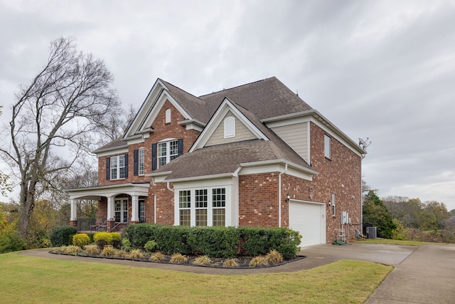 view of front of property featuring covered porch, a garage, and a front lawn