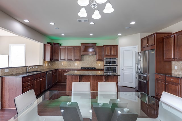 kitchen featuring premium range hood, decorative backsplash, decorative light fixtures, a kitchen island, and stainless steel appliances