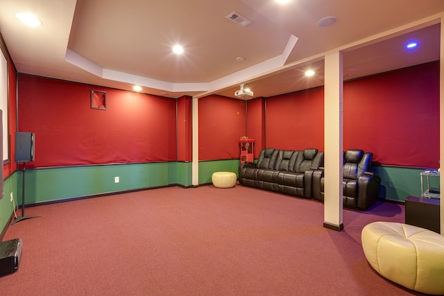 carpeted home theater room with a raised ceiling