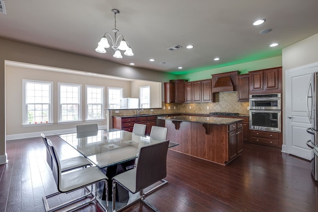 kitchen featuring kitchen peninsula, pendant lighting, dark hardwood / wood-style floors, and custom exhaust hood