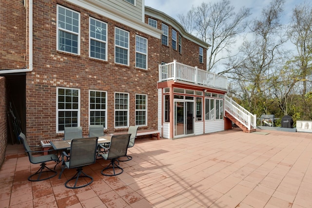 rear view of property with a patio, a balcony, and a sunroom